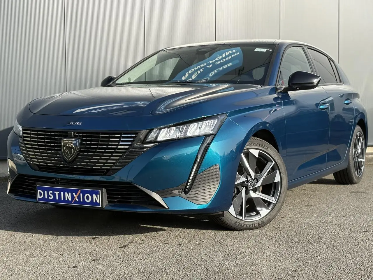 Peugeot 308 Hybrid bleu Obsession vue 3/4 avant droit avec calandre noire et jantes alliage 17 pouces.