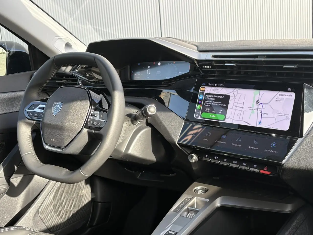 Vue intérieure du poste de conduite de la Peugeot 308 Hybrid 2025, volant cuir et écran tactile de navigation Apple CarPlay.