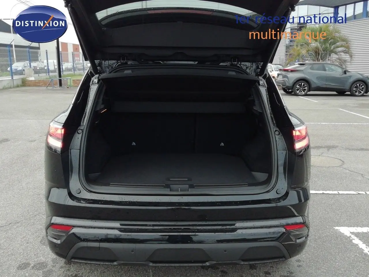Vue arrière du Renault Austral E-Tech Full Hybrid noir étoile métal avec coffre ouvert, montrant l'espace de chargement vide.