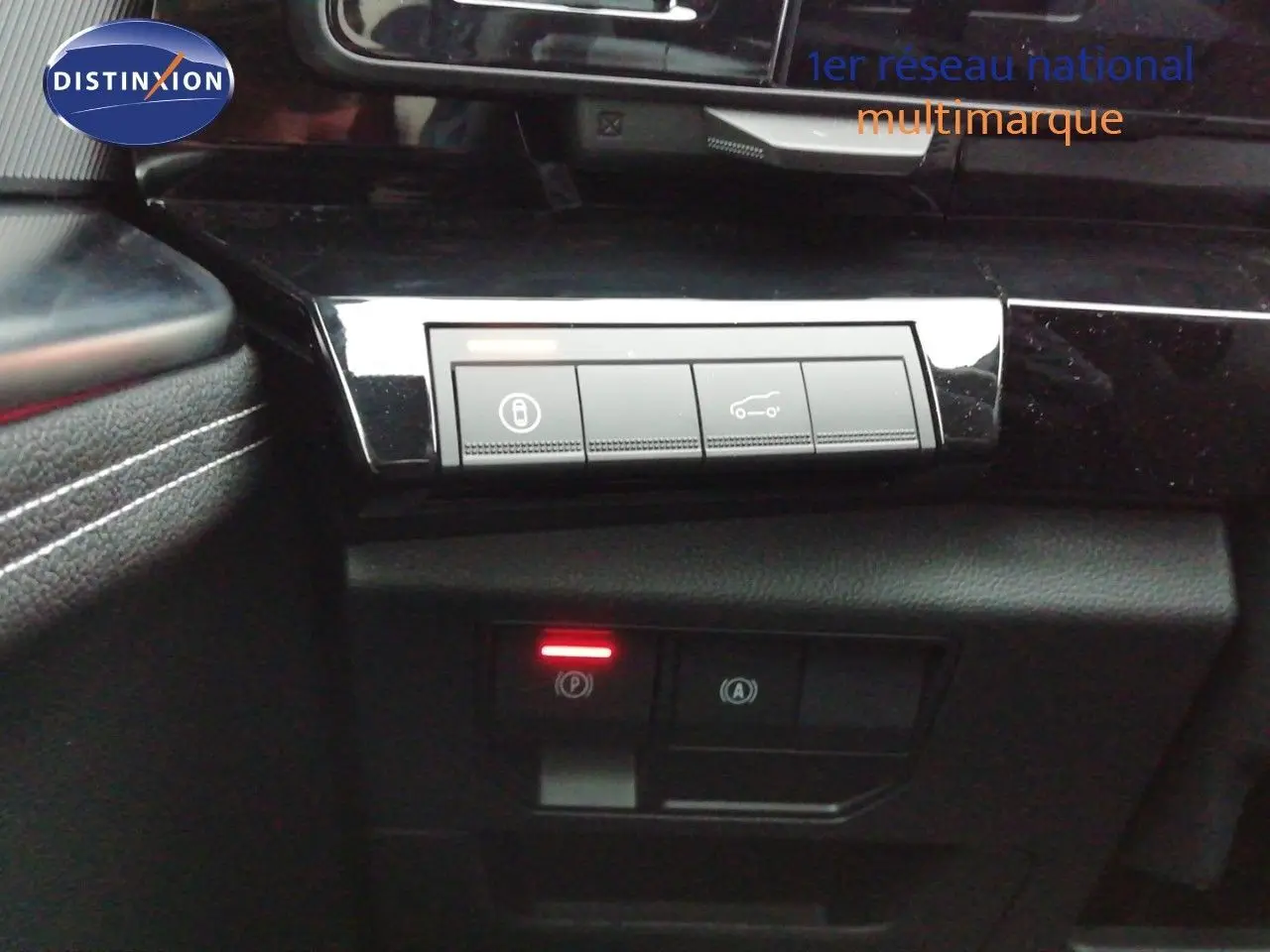 Gros plan sur les commandes intérieures noires brillantes du Renault Austral E-Tech, avec éclairage rouge du frein à main.