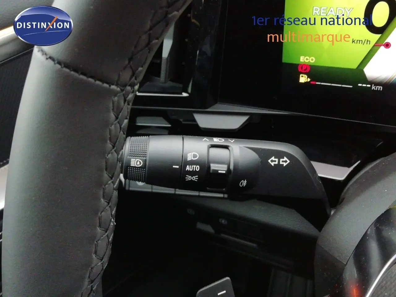 Gros plan sur la commande des feux et clignotants du Renault Austral noir étoile métal, avec tableau de bord numérique en arrière-plan.