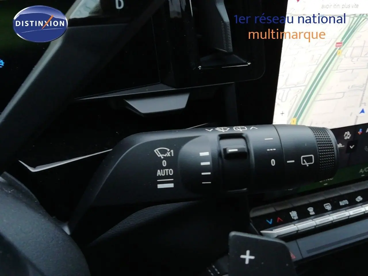 Gros plan sur la commande d’essuie-glace du Renault Austral noir étoile métal, avec écran tactile et carte GPS en arrière-plan.