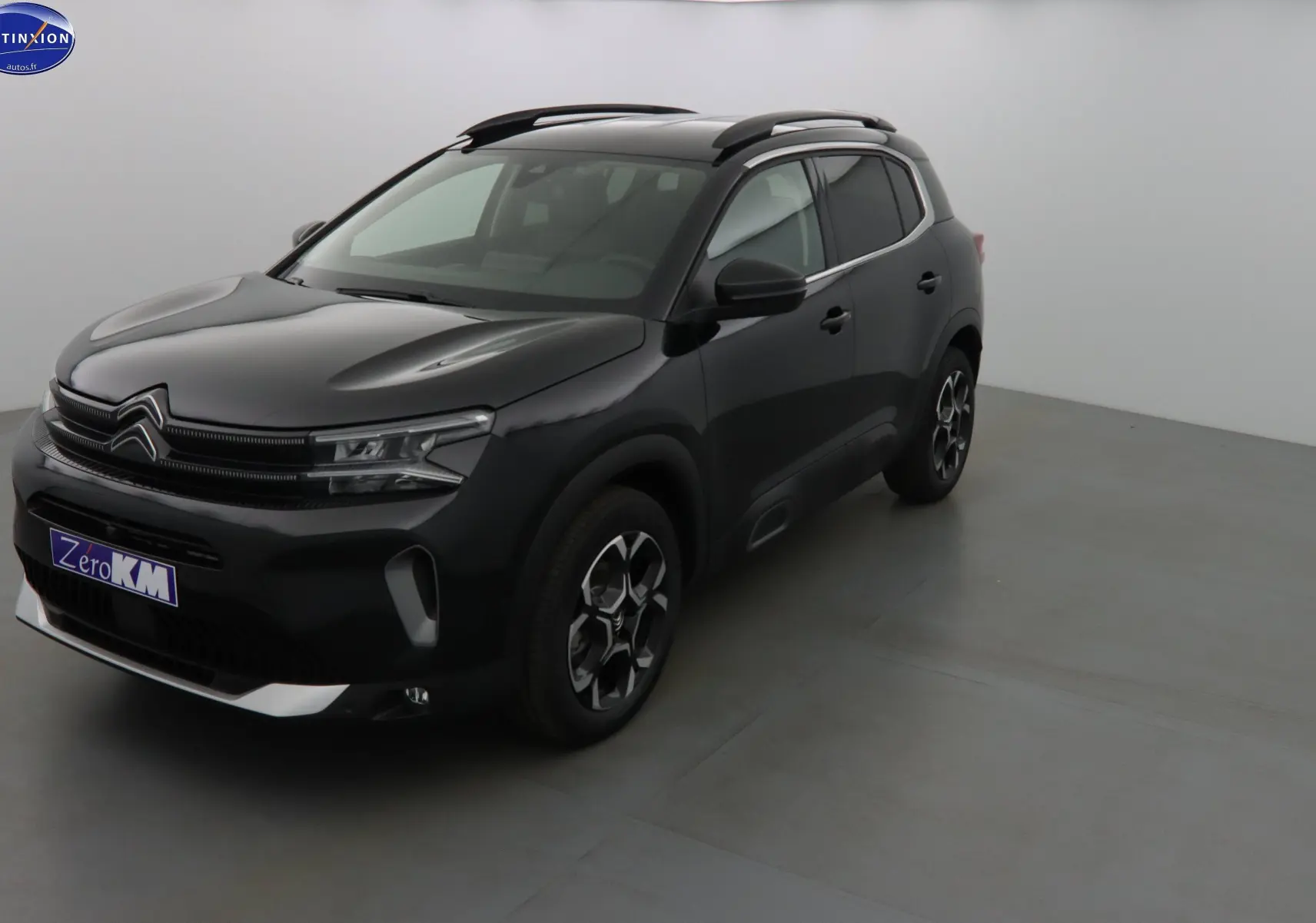 Citroën C5 Aircross noir métal en 3/4 avant droit, avec jantes bi-ton et barres de toit visibles.