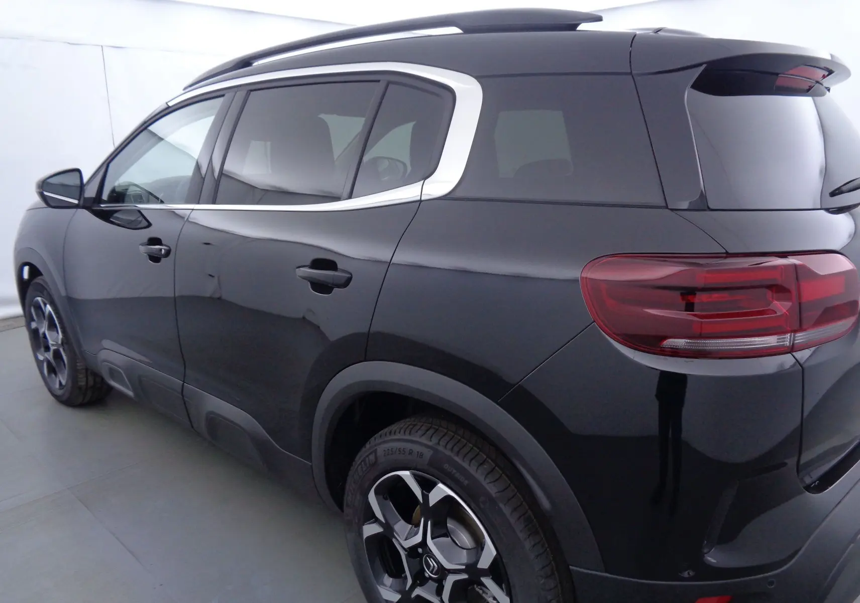 Vue 3/4 arrière côté gauche d'un Citroën C5 Aircross noir métal avec jantes bi-ton et vitres teintées.