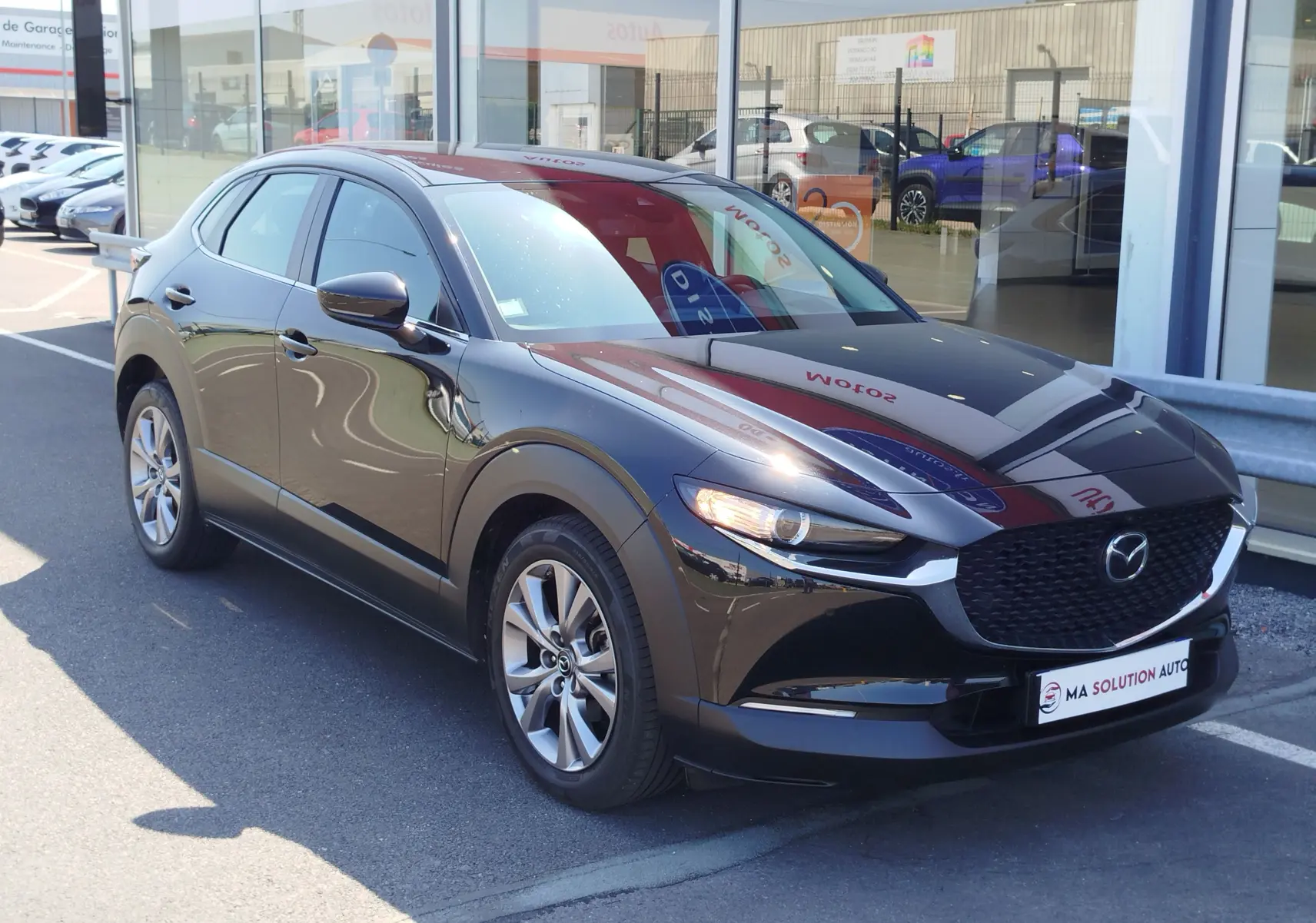 Vue 3/4 avant droite d'un Mazda CX-30 noir 2020 avec calandre noire et jantes alliage visibles.