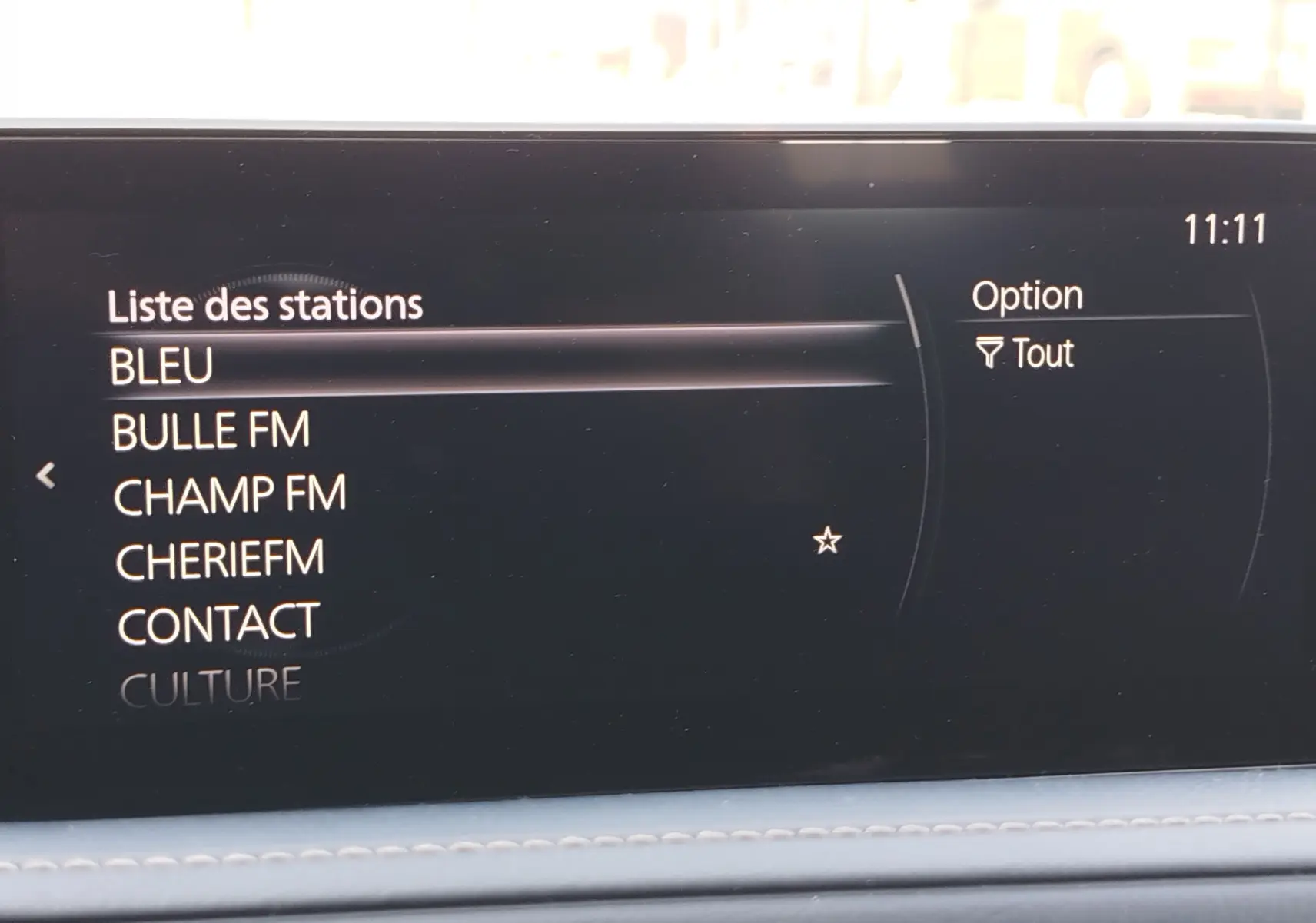 Écran multimédia intérieur du Mazda CX-30 affichant la liste des stations radio avec interface noire et texte blanc.
