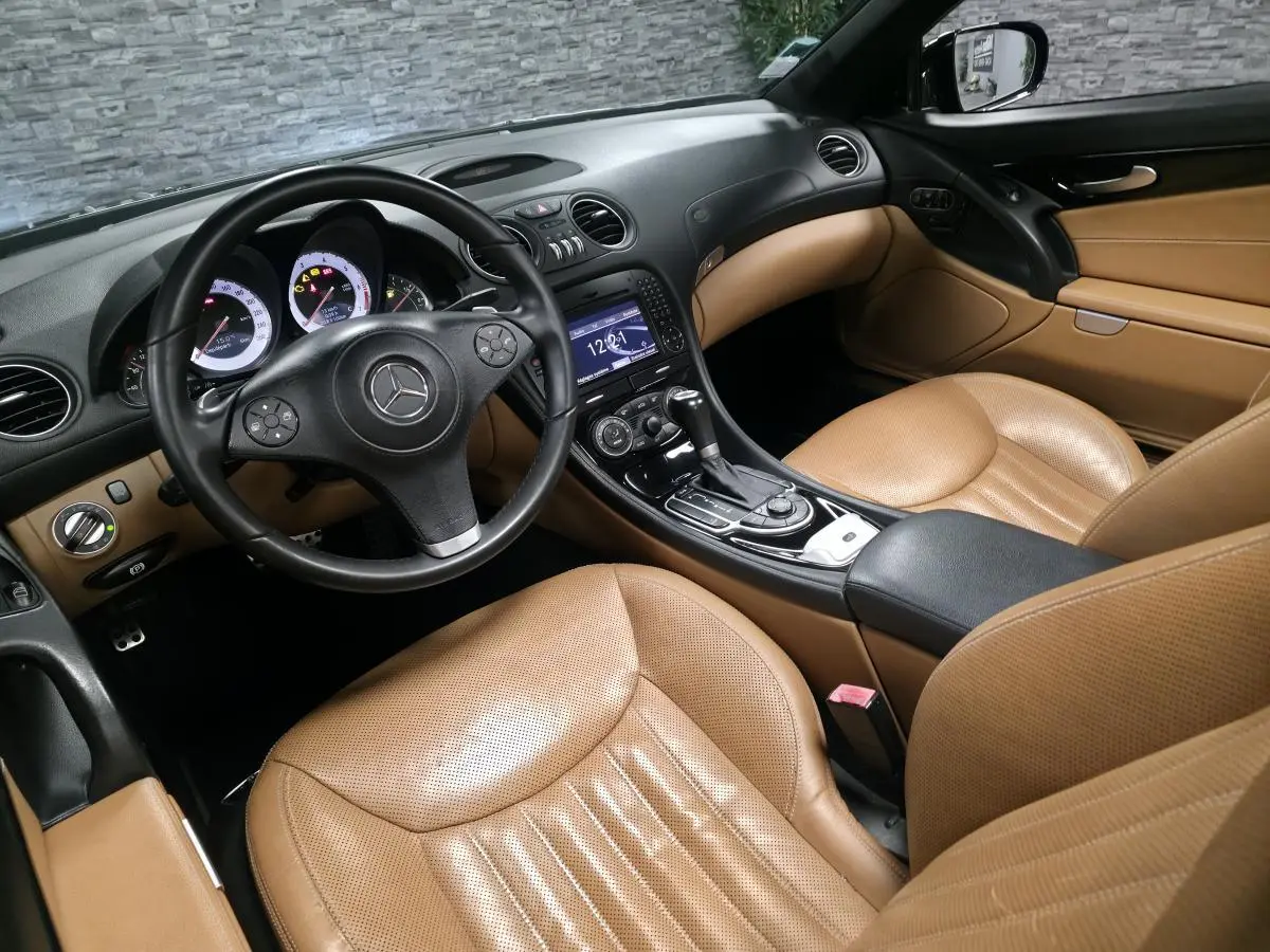 Vue intérieure côté conducteur de la Mercedes SL 500 noire de 2008 avec sièges cuir Nappa beige et console centrale noire.