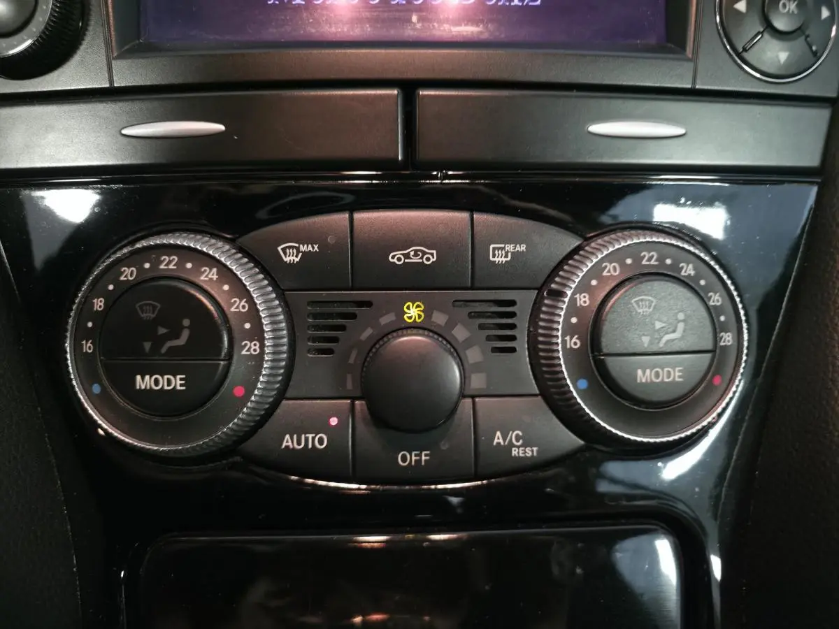 Gros plan sur la console centrale noire du Mercedes SL 500 2008, mettant en valeur les commandes de climatisation automatique.