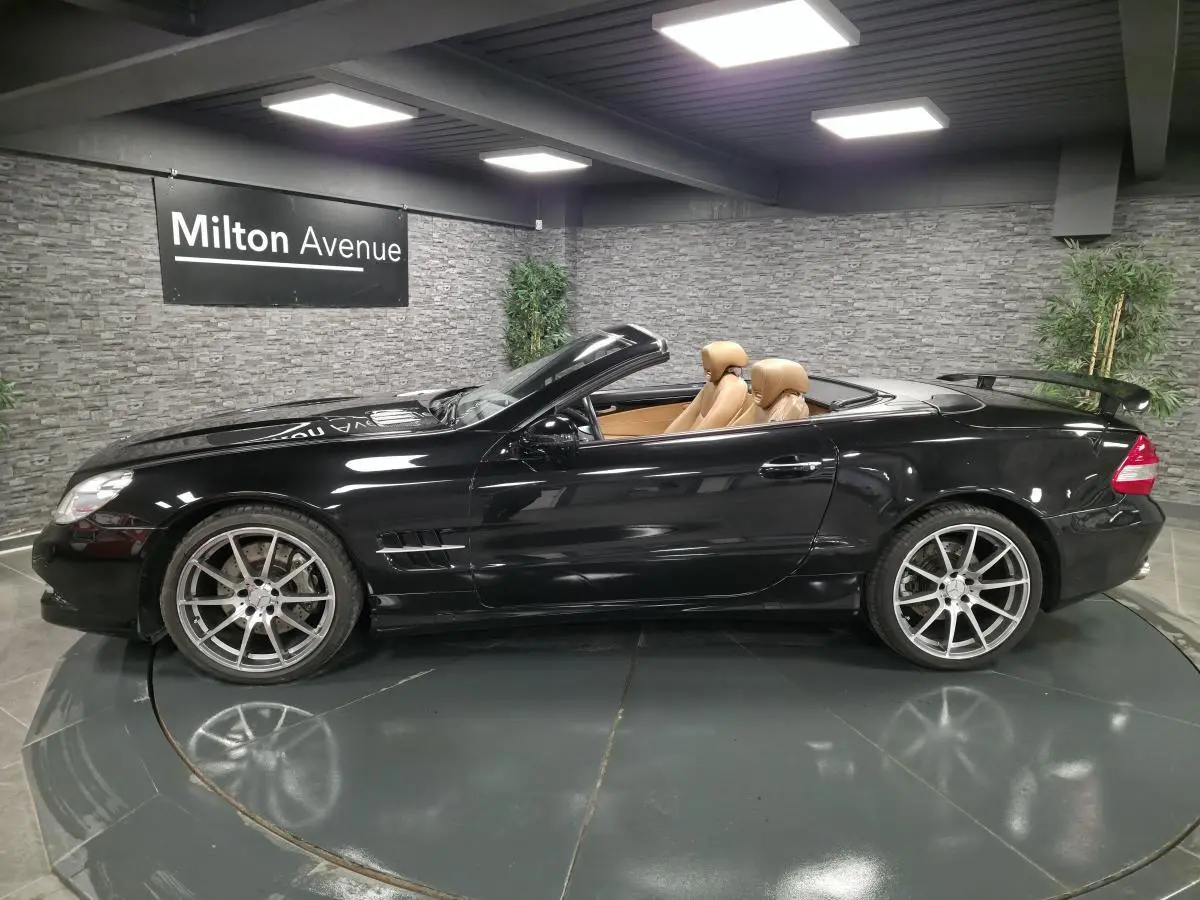 Vue de profil côté gauche d'une Mercedes SL 500 noire cabriolet avec intérieur cuir beige et jantes alliage 19 pouces.