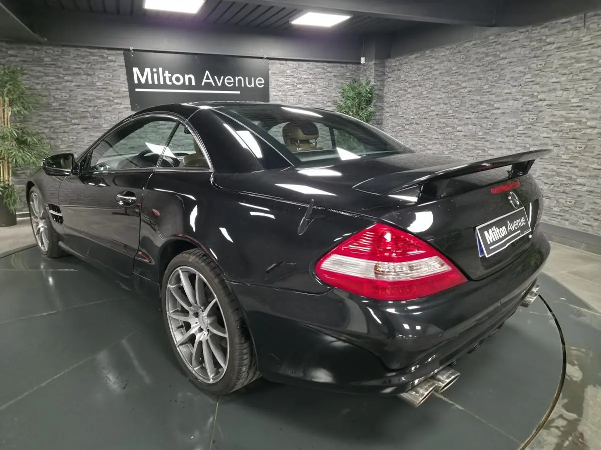 Mercedes SL 500 noir vu en 3/4 arrière droit, avec jantes alliage 19 pouces et aileron arrière AMG.