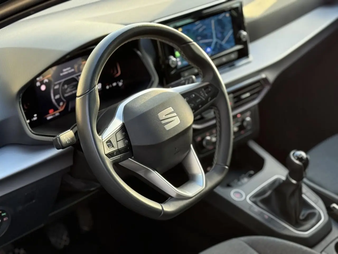 Vue rapprochée de l'intérieur de la SEAT Ibiza 2025, volant cuir multifonction et levier de vitesses manuelle visibles.