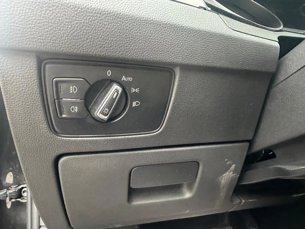 Gros plan sur le bouton de commande des phares sur la planche de bord noire d'une Volkswagen Passat gris foncé 2021.