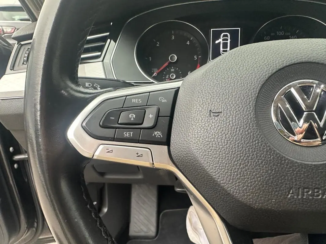 Gros plan sur le volant multifonctions en cuir de la Volkswagen Passat Business 2021 avec commandes au volant visibles.