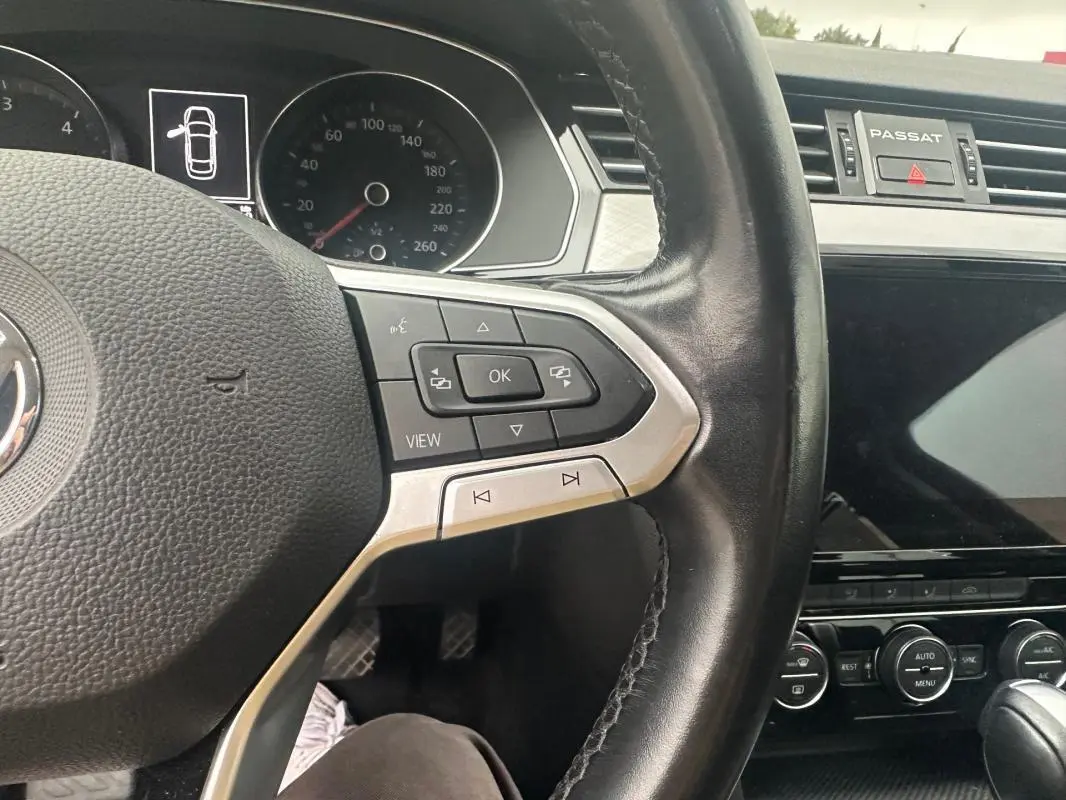 Vue rapprochée du volant cuir multifonctions et du tableau de bord numérique de la Volkswagen Passat gris foncé Business 2021.