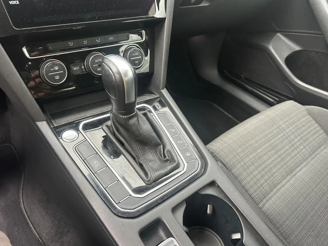 Vue rapprochée de la console centrale de la Volkswagen Passat Business 2021 avec levier de vitesse automatique et sièges gris à motifs.