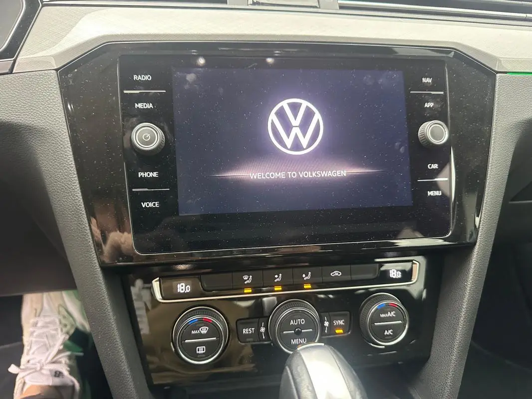 Vue rapprochée du tableau de bord de la Volkswagen Passat Business gris foncé, mettant en valeur l'écran tactile et les commandes de climatisation.