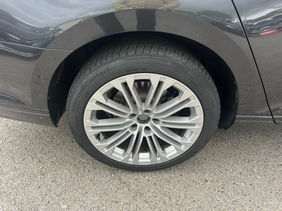 Gros plan sur la roue avant gauche de la Volkswagen Passat Business gris foncé avec jante alliage 17 pouces multi-branches.