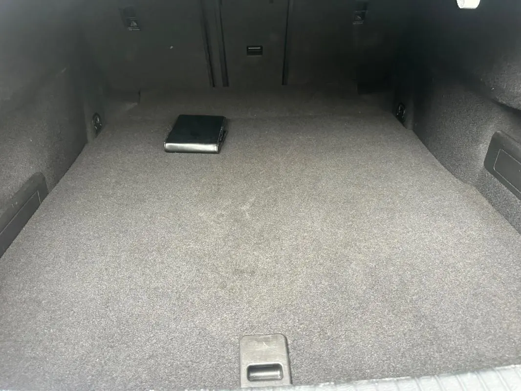 Coffre spacieux gris foncé de la Volkswagen Passat Business 2021, avec un manuel posé à l'arrière.