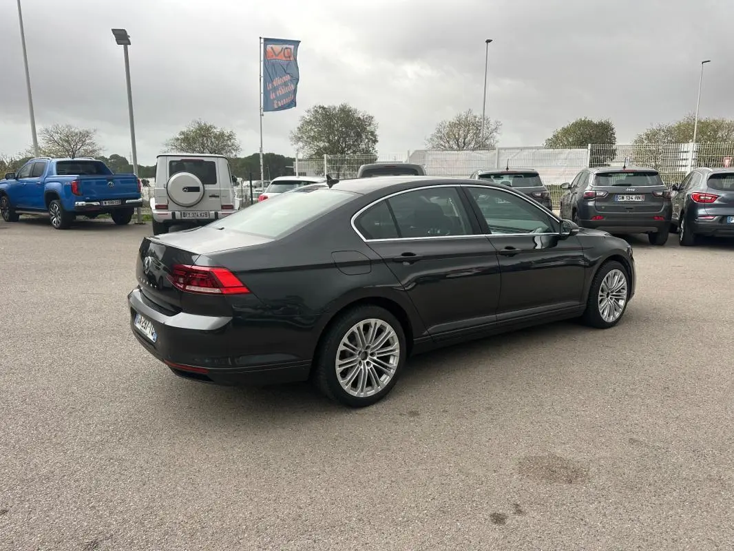 Volkswagen Passat Business gris foncé vue 3/4 arrière droit sur parking avec jantes alliage 17 pouces.