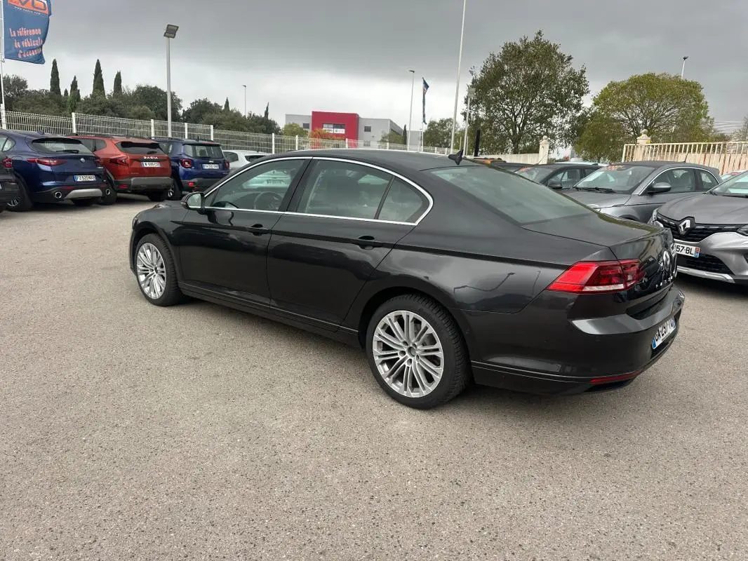 Volkswagen Passat gris foncé vue 3/4 arrière droit, jantes alliage 17 pouces, stationnée en extérieur sur parking.