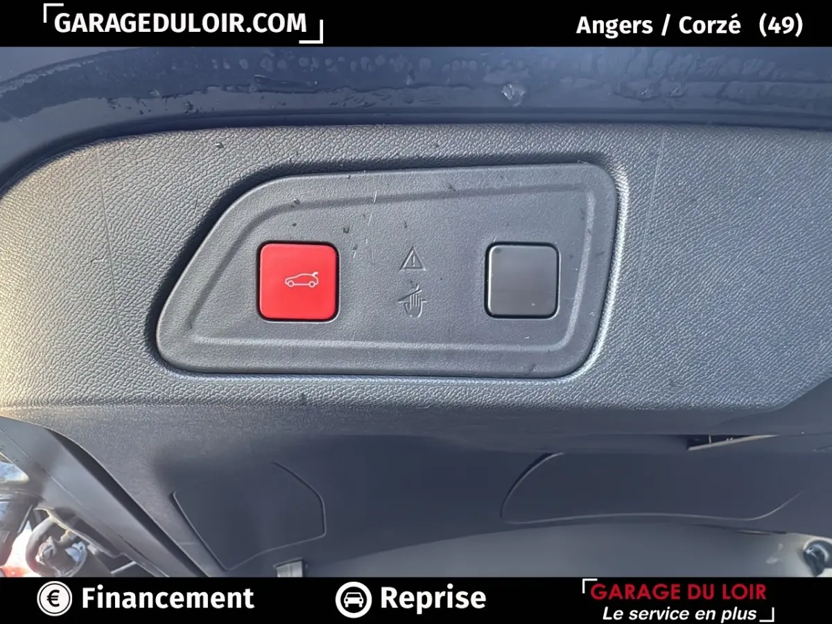 Gros plan sur le bouton rouge d'ouverture du coffre dans le coffre d'un Citroën C5 Aircross noir 2025.