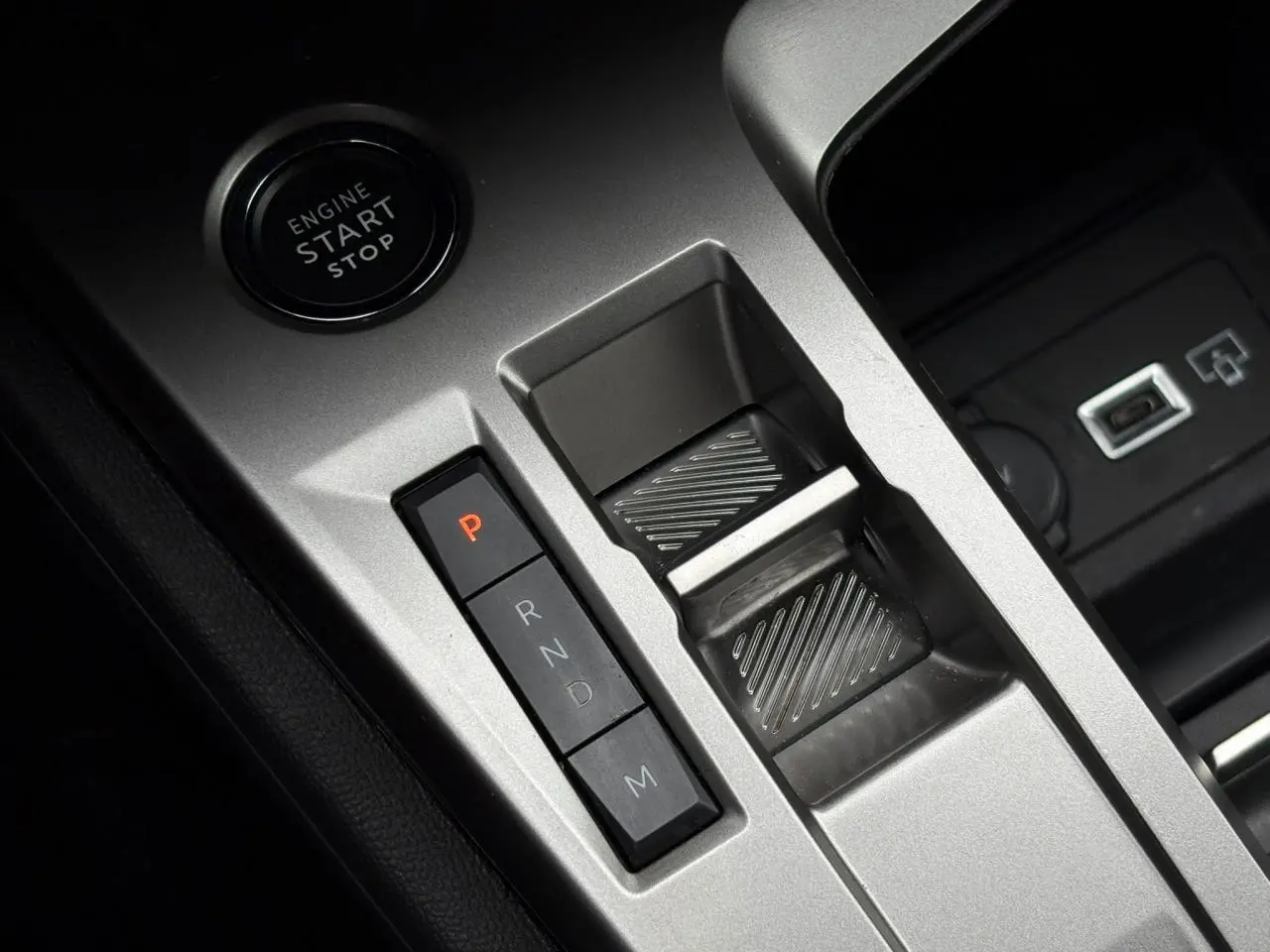 Gros plan sur la console centrale grise avec bouton start/stop et commandes de la boîte auto de la Peugeot 308 SW Hybrid.