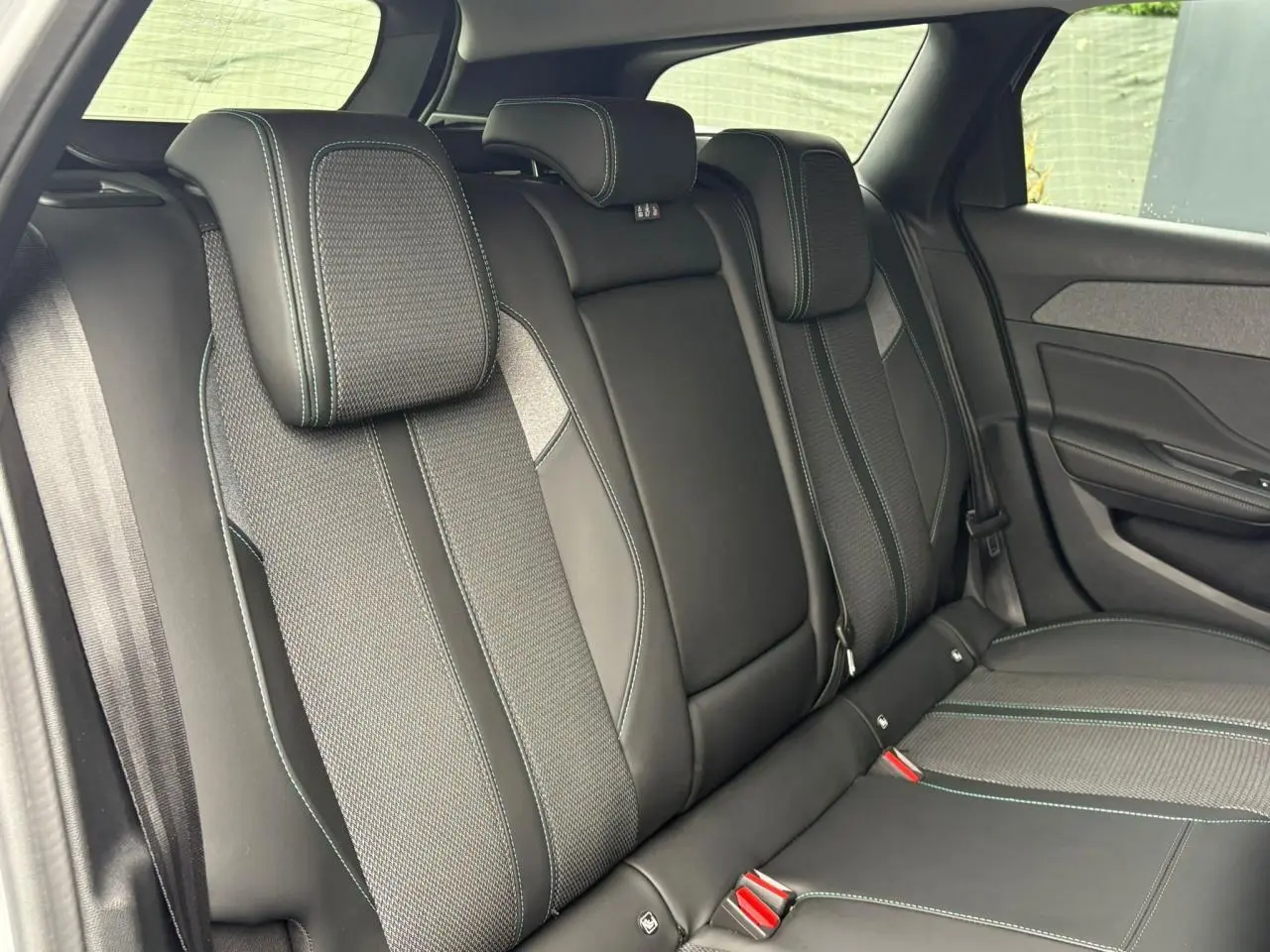 Vue intérieure des sièges arrière en cuir noir avec surpiqûres contrastantes dans une Peugeot 308 SW Hybrid 2025.