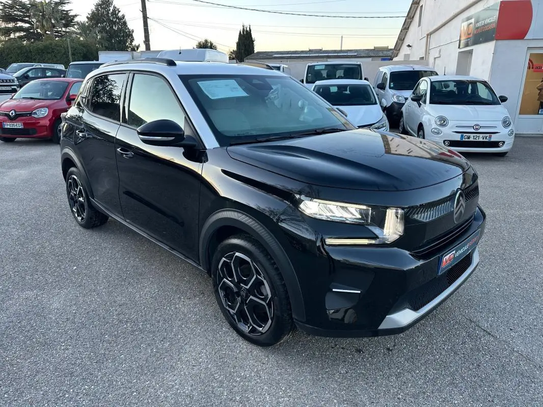 Vue 3/4 avant droite d'une Citroën C3 noire 2025 avec jantes alliage 17 pouces et barres de toit visibles.