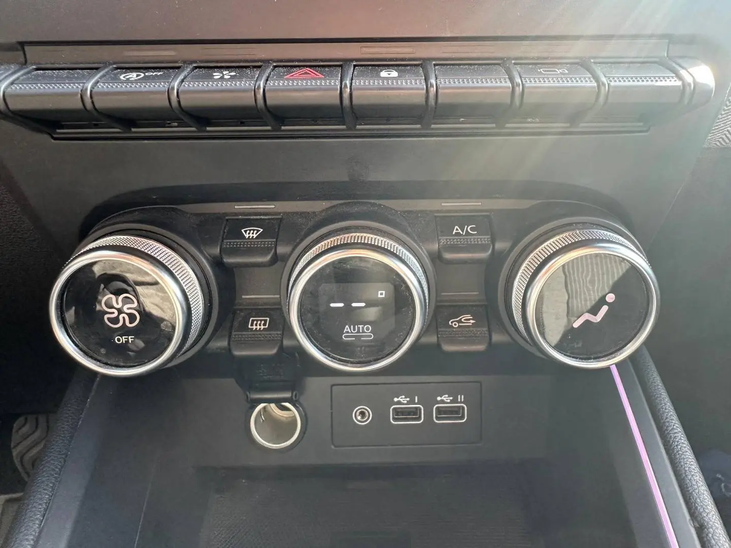 Vue rapprochée des commandes de climatisation et des ports USB de la Renault Clio Rouge Flamme 2025.