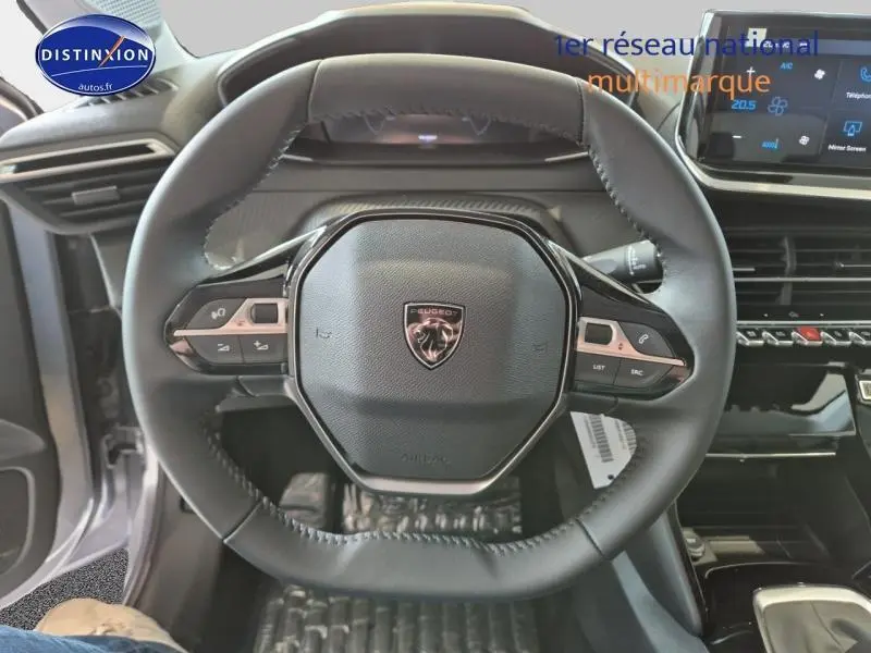 Vue rapprochée du volant cuir noir de la Peugeot 208 1.2 100ch Allure, avec commandes intégrées et tableau de bord moderne.