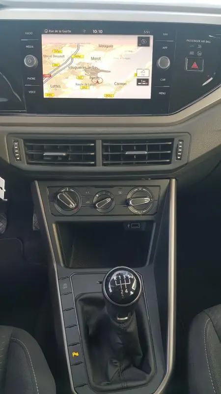 Vue intérieure centrée sur la console centrale d'une Volkswagen Polo noire 2018 avec levier de vitesses manuel et écran tactile GPS.