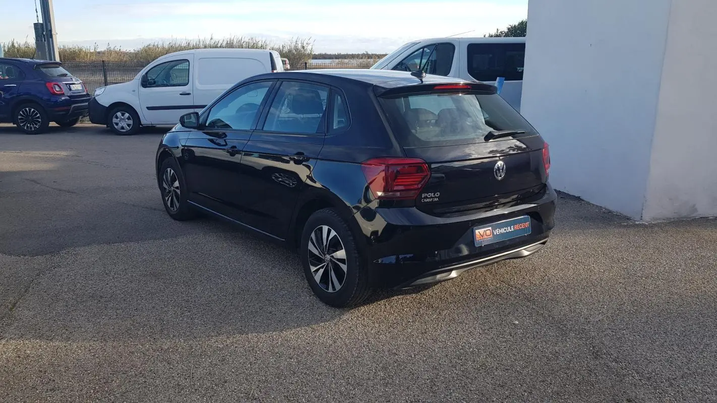 Volkswagen Polo noire vue 3/4 arrière côté gauche, avec jantes alliage et feux arrière distinctifs.