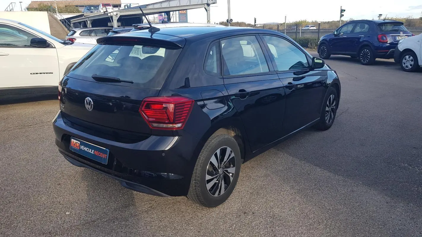 Volkswagen Polo noir vue 3/4 arrière droit, avec jantes alliage 15 pouces et feux arrière distinctifs.