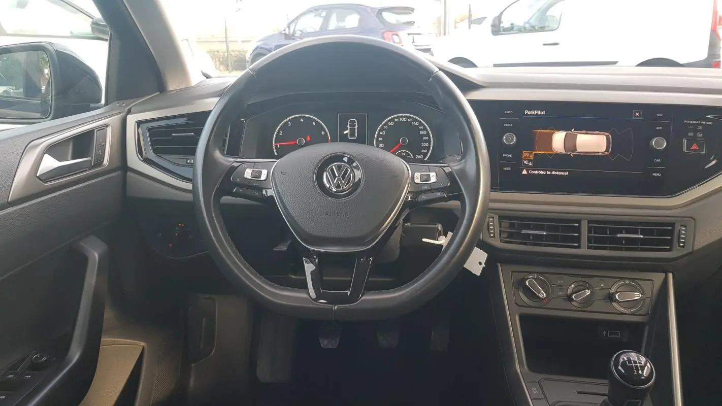 Vue intérieure frontale du volant cuir multifonctions et tableau de bord numérique de la Volkswagen Polo noire 2018.