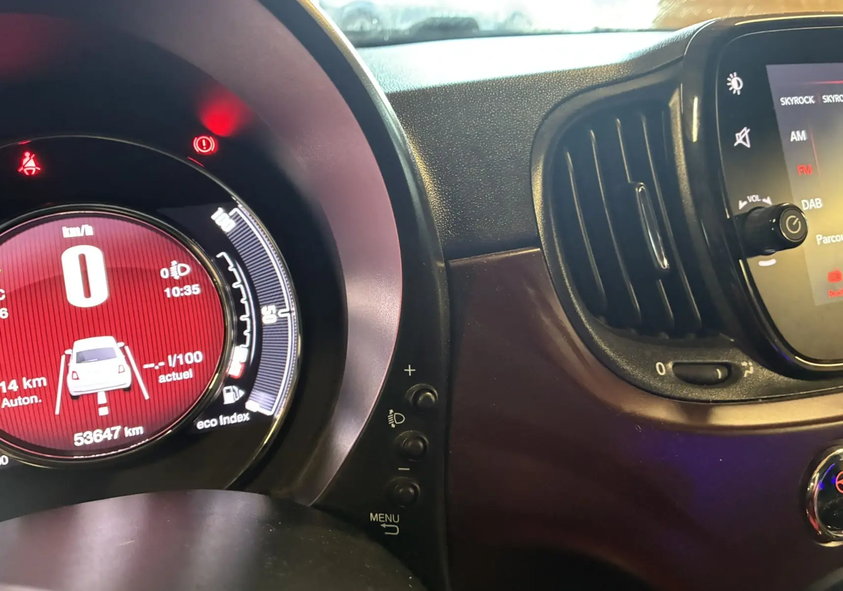 Tableau de bord et console centrale d'une Fiat 500 blanche, vue rapprochée de l'instrumentation et écran multimédia.