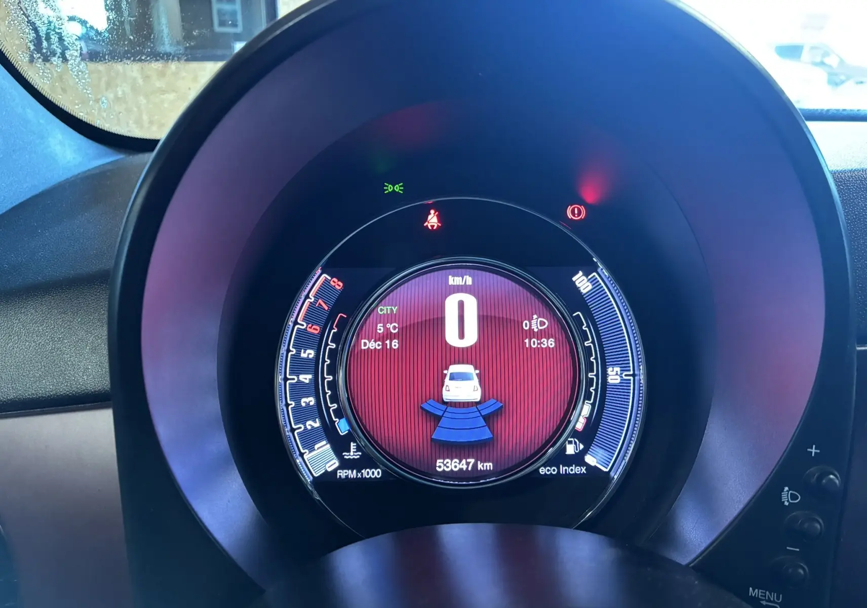 Vue rapprochée du tableau de bord numérique de la Fiat 500 blanche, affichant la vitesse à 0 km/h et le compteur kilométrique.