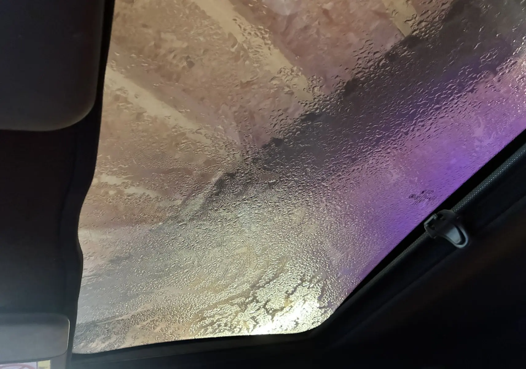 Vue intérieure du toit ouvrant panoramique d'une Fiat 500 blanche, avec condensation visible sur le verre.