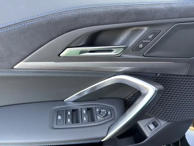 Détail de la porte côté conducteur du BMW X2 noir 2025, avec commandes fenêtres et poignée alu intégrée.