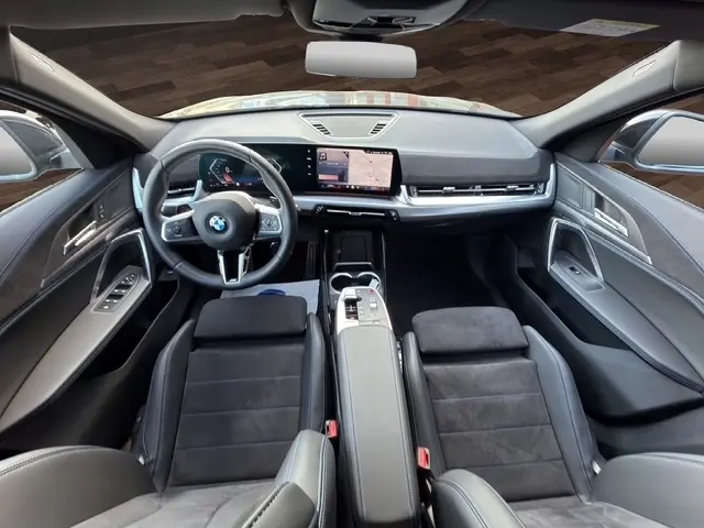 Vue intérieure avant du BMW X2 sDrive20d M Sport 2025 noir, volant cuir alu multifonctions et écran tactile central.