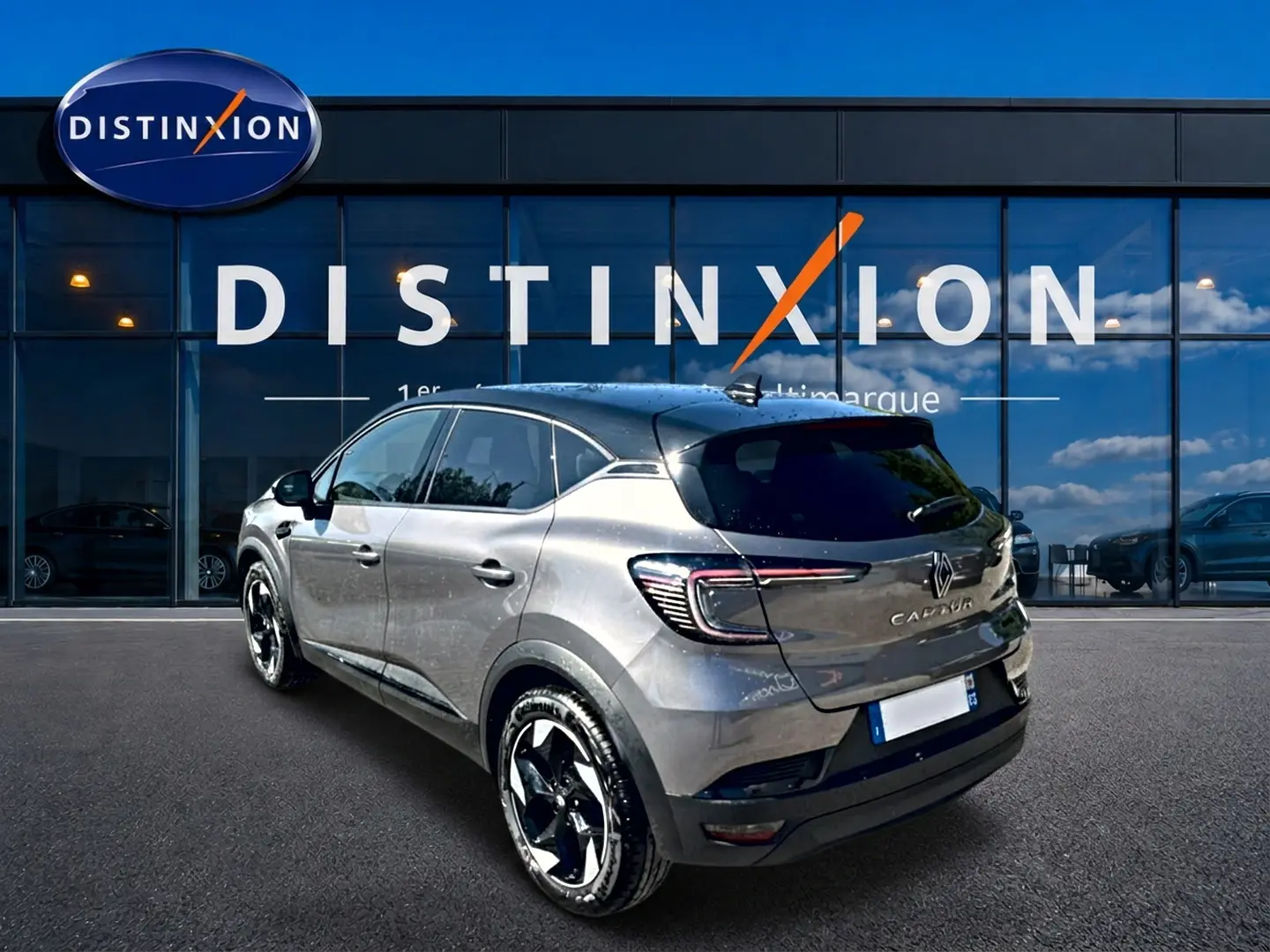 Renault Captur gris cassiopée en 3/4 arrière droit, avec feux LED et jantes alliage noires devant showroom Distinxion.