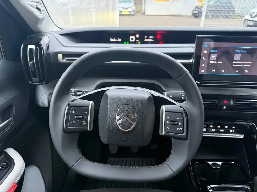 Vue intérieure centrée sur le volant noir de la Citroën C3 2025 avec tableau de bord digital et écran tactile.