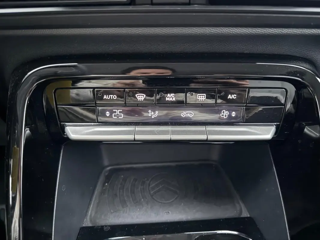 Gros plan sur la console centrale de la Citroën C3 gris, montrant les commandes de climatisation automatique et le rangement avec logo Citroën.