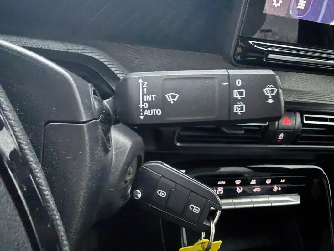 Gros plan sur la commande d’essuie-glace et la clé de contact dans l’habitacle noir de la Citroën C3 gris 2025.