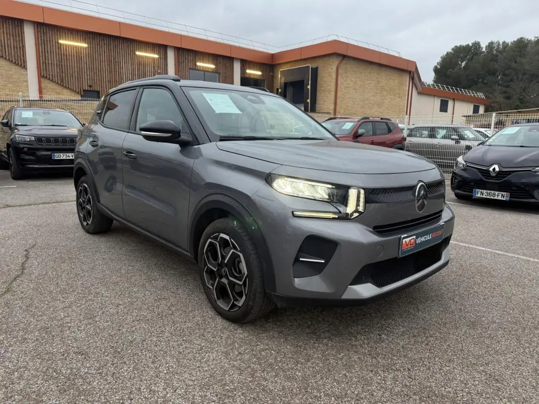 Vue 3/4 avant droit d'une Citroën C3 gris métallisé avec jantes alliage 17 pouces et barres de toit noires.