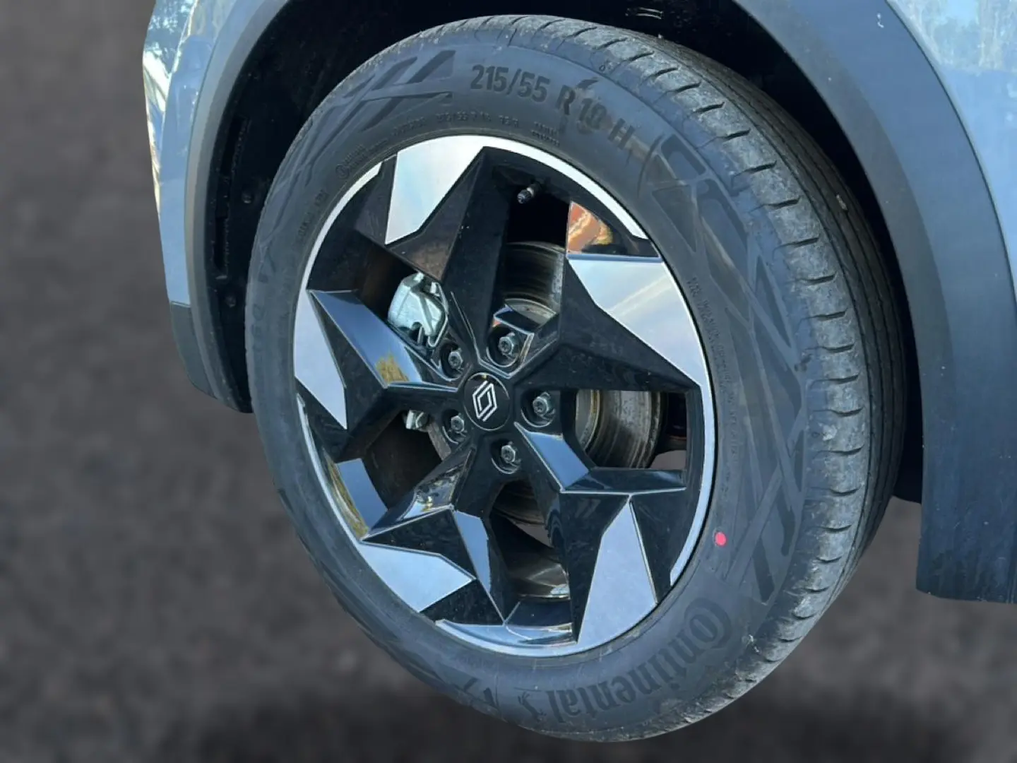 Gros plan sur la roue avant droite du Renault Captur gris rafale, mettant en valeur la jante alu au design étoilé noir et argent.