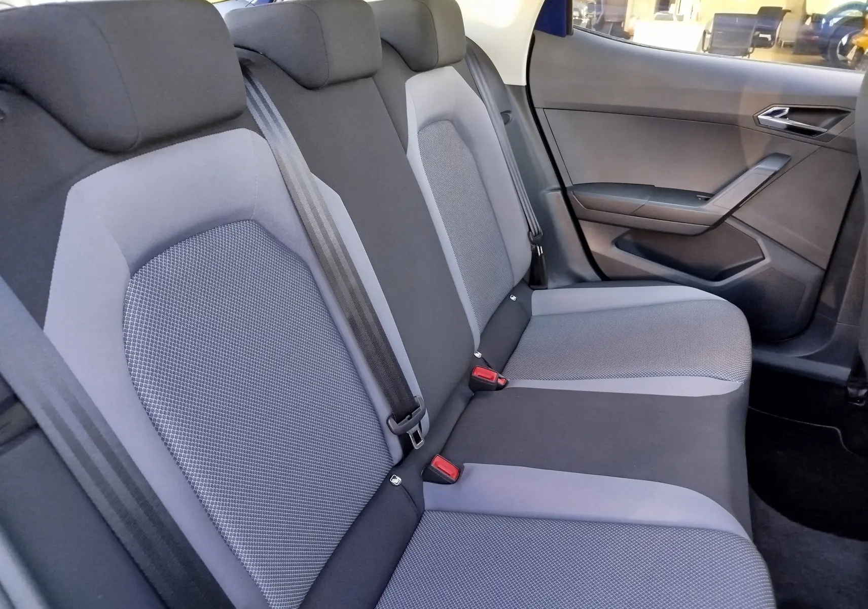 Vue latérale du siège arrière gris et noir du SEAT ARONA 2019, montrant les ceintures et la portière côté droit.