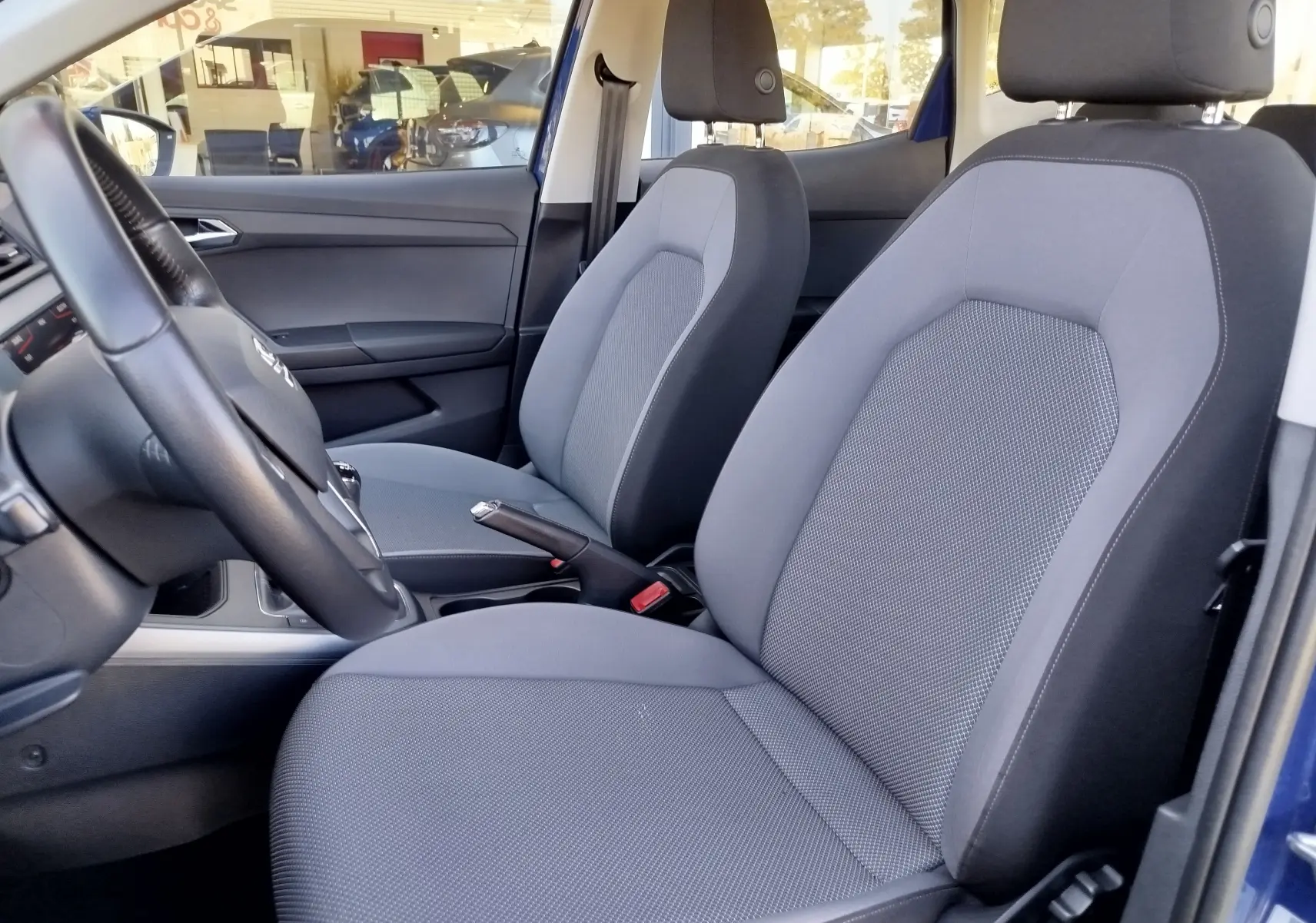 Vue intérieure côté conducteur du SEAT Arona bleu électrique 2019, sièges gris et volant multifonction.