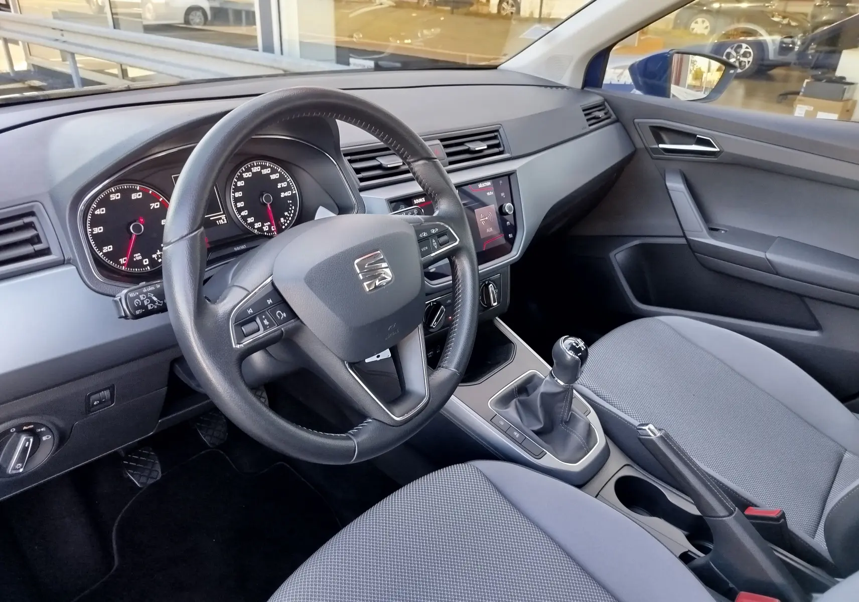 Intérieur de la SEAT Arona 2019 vu côté conducteur, volant multifonction, tableau de bord et sièges gris.