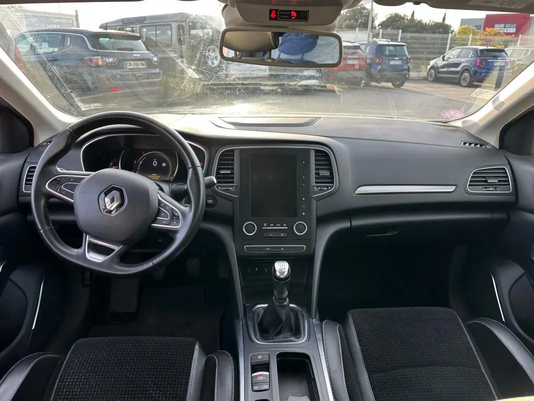 Intérieur noir de la Renault Mégane Break IV TCe 130, vue frontale du tableau de bord avec volant cuir et boîte manuelle.