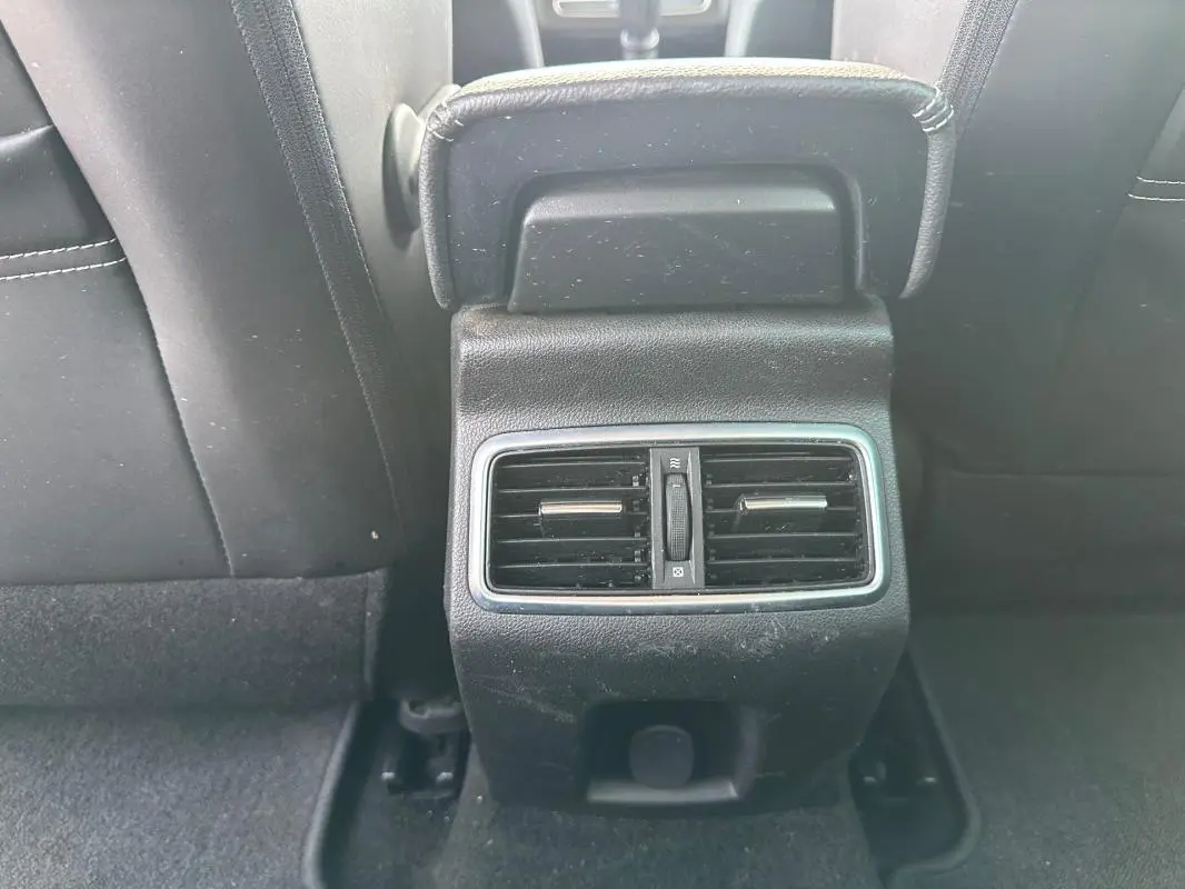 Bouche d'aération arrière noire encadrée de chrome entre les sièges avant d'une Renault Mégane Break gris clair.